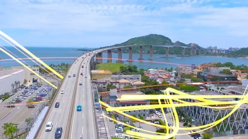 Avenida movimentada vista do alto, com linhas de luz amarelas sobre a cidade